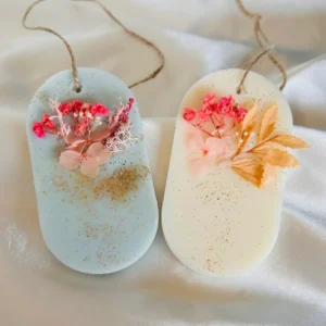Suspensions parfumées artisanales en cire de soja, décorées de fleurs séchées et de paillettes dorées, avec une cordelette en lin.